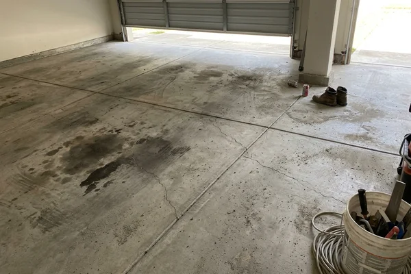 Cracked, oil-stained bare garage slab before coating
