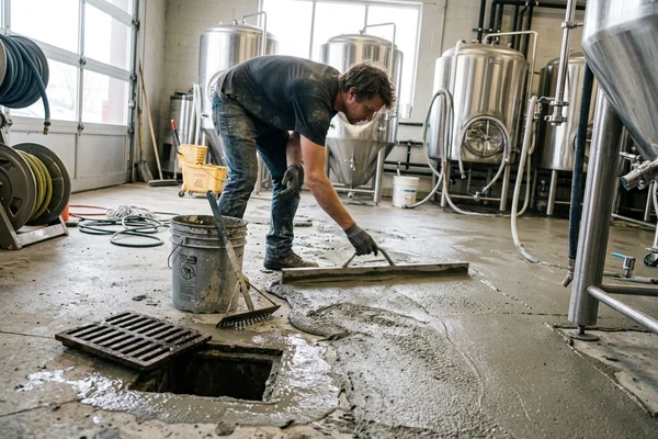 Cementitious urethane being screeded across a brewery floor near a drain