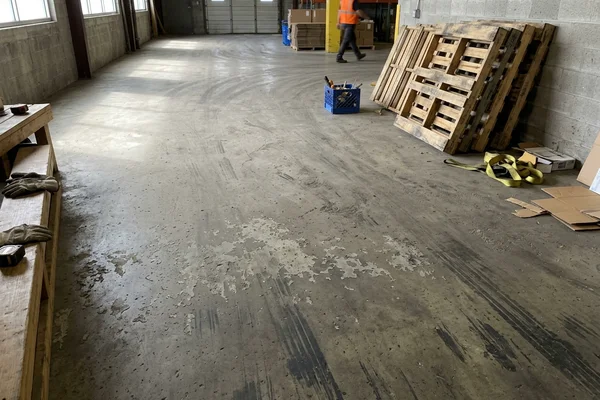 Dull, dusty warehouse slab with scuff marks before polishing
