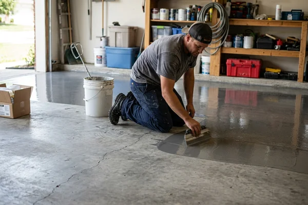 Installer spreading polyaspartic topcoat across a prepped garage slab