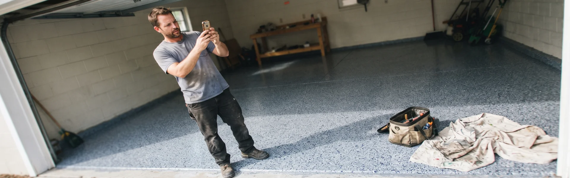 Installer photographing a finished flake epoxy garage floor for a project record