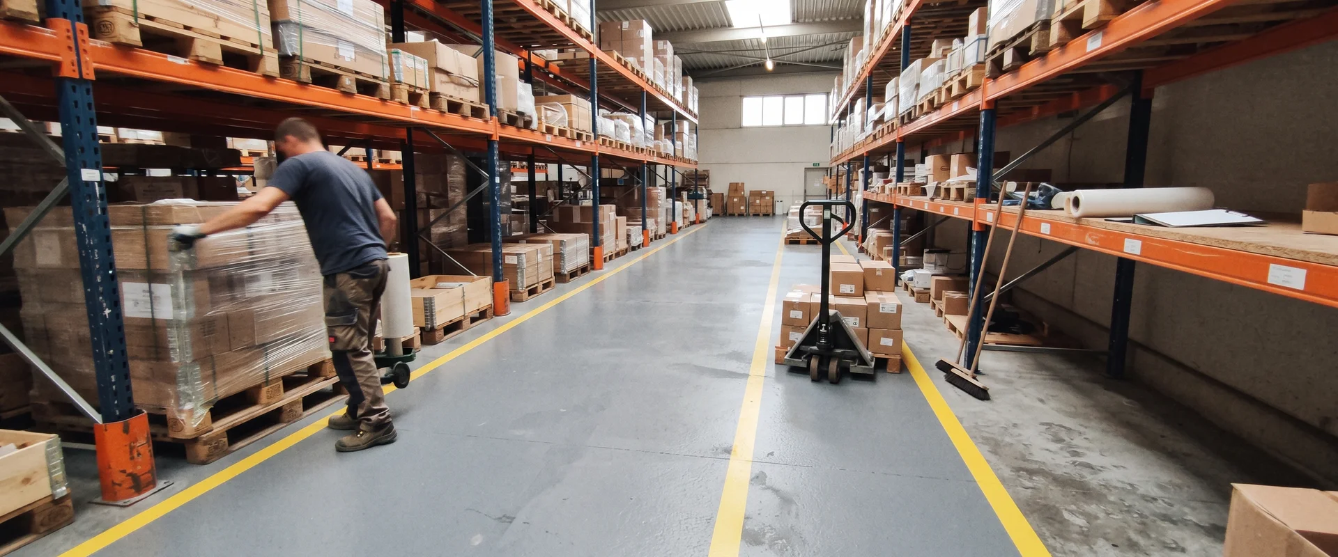 Warehouse floor with a fresh resinous coating and aisle markings between pallet racking